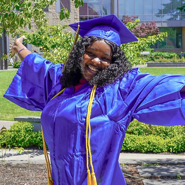 grad in blue regalia with arms outspread